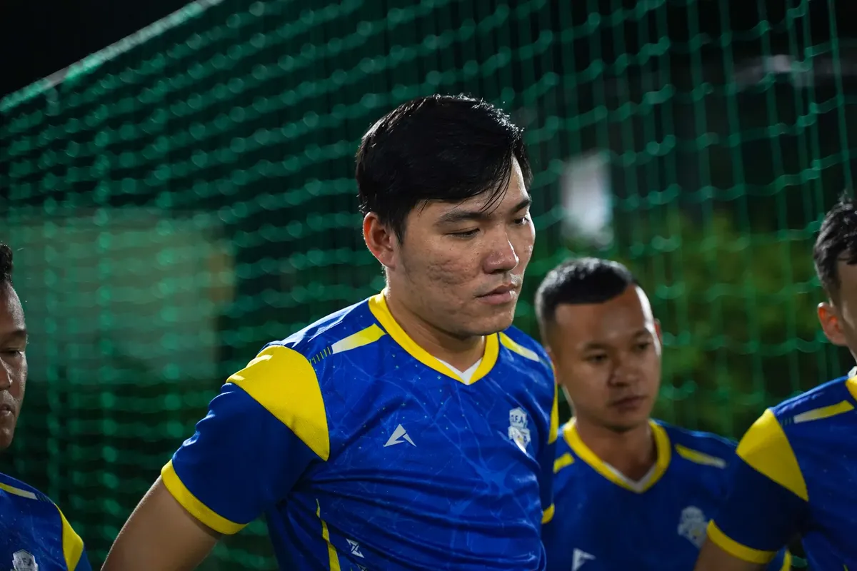 Asian football team gathers in vibrant uniforms during a night game. Focus on teamwork and sportsmanship.