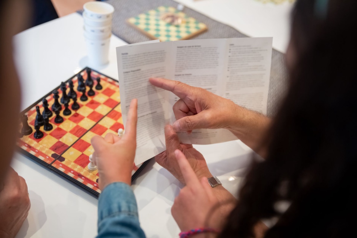 Adult and child reading chess instructions while setting up a chess game.