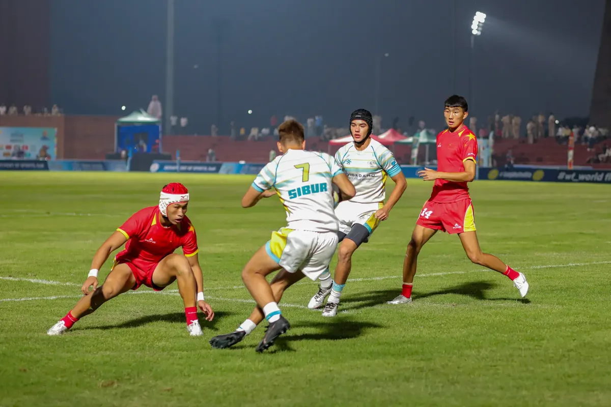 Rugby players in action during a nighttime match under stadium lights.