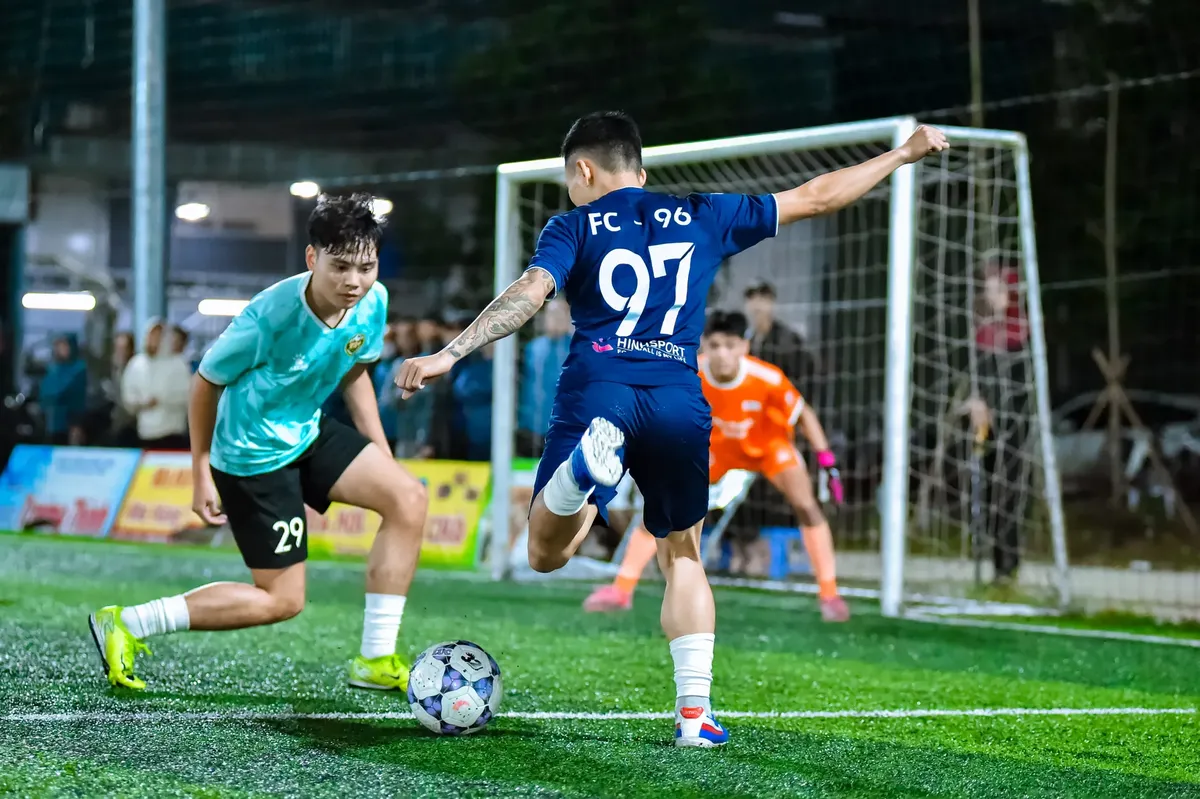 Dynamic football action capture during an evening match in Hà Nội, Vietnam.