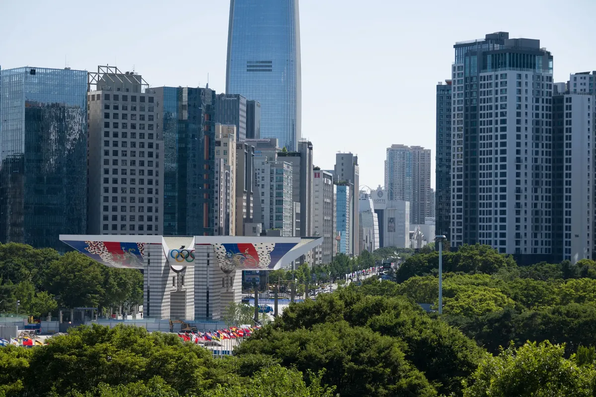 A view of Seoul's modern skyline, featuring the iconic Olympic Gateway, under a clear blue sky.