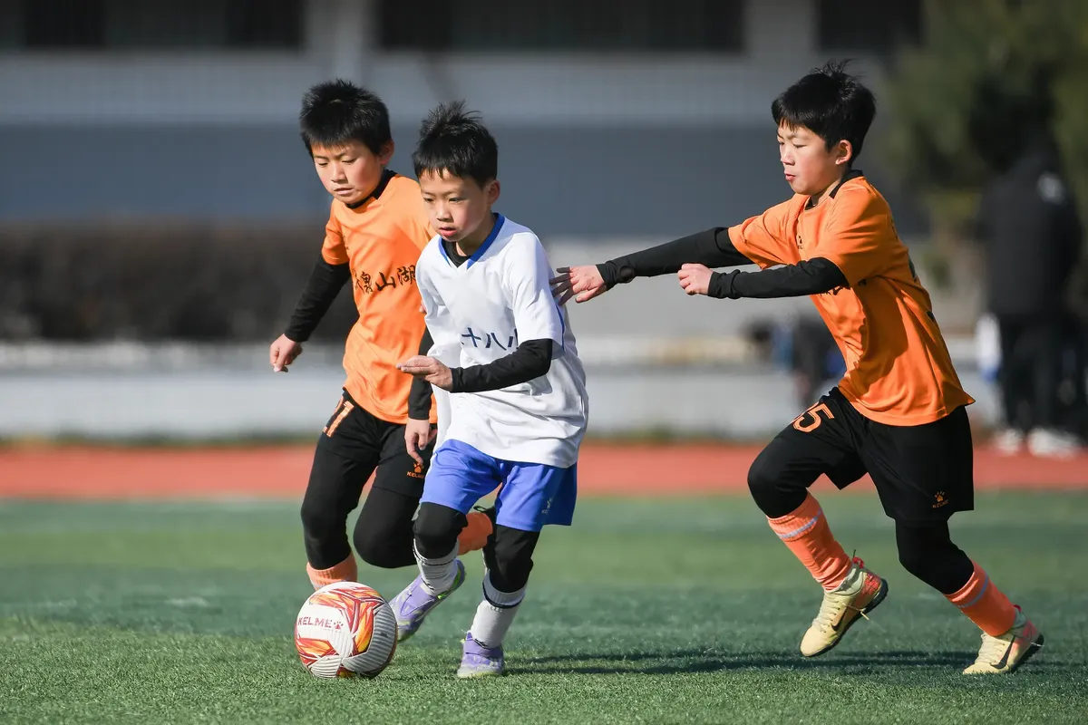 太陽の下、外での競技的なサッカーのプレイを performing する子供たち。