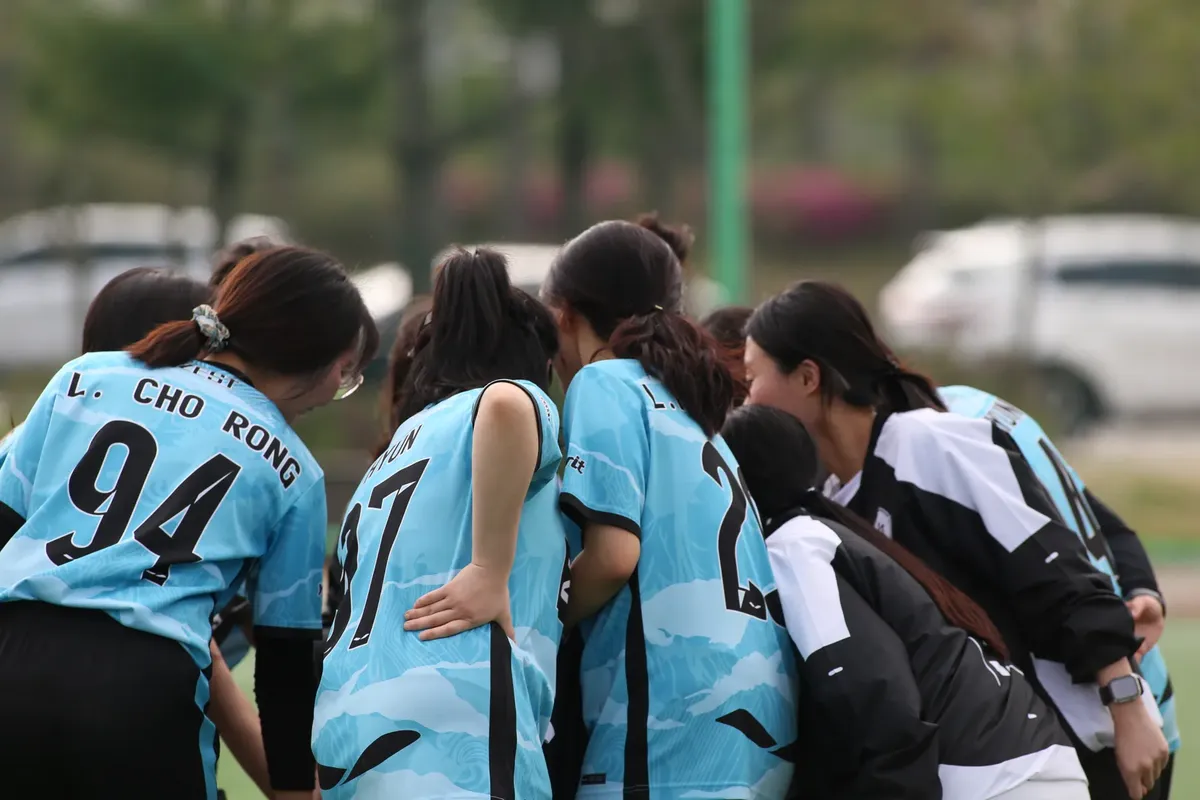 試合中のチームで女性フットボール選手が集まってチームのモチベーションアップを図る様子。